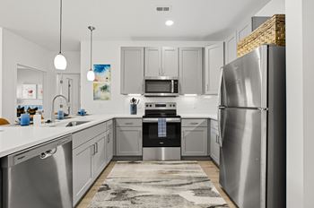 A modern kitchen with stainless steel appliances and white countertops.